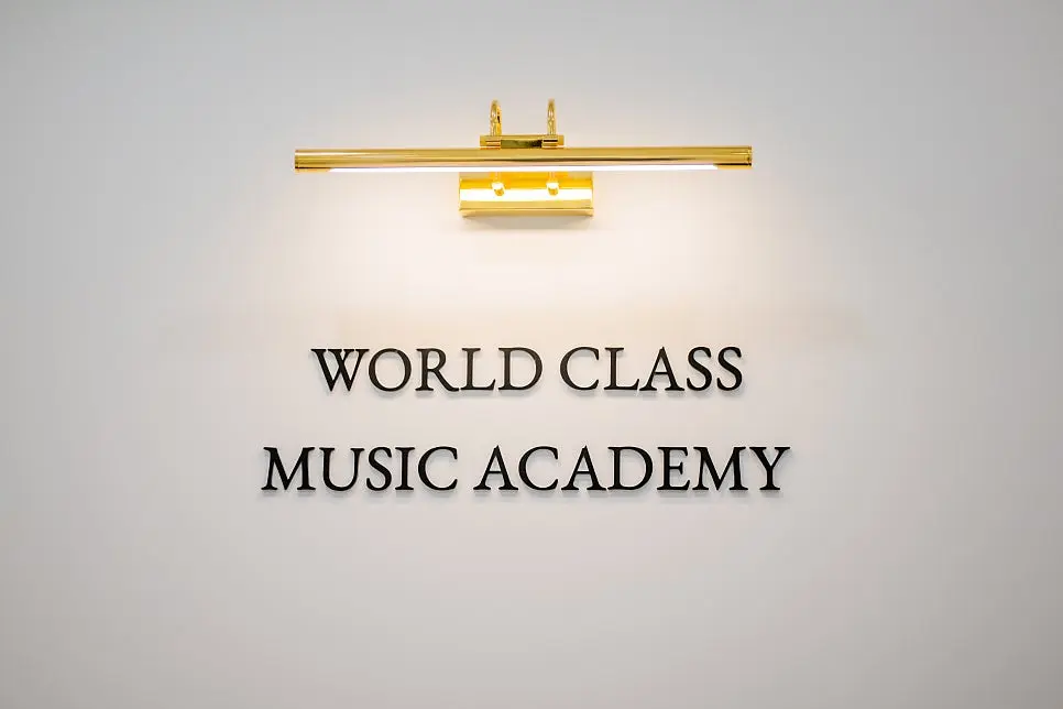WORLD CLASS MUSIC ACADEMY 사인과 금색 조명이 있는 전실 벽